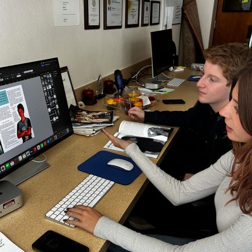 Two students sit next to each other before a computer screen with a layout showing an athlete with the heading EVERY BODY BELONGS