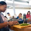 Student chopping food on cutting board in a large room