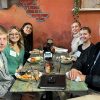 Group of five students sit with an older gentleman at a restaurant table