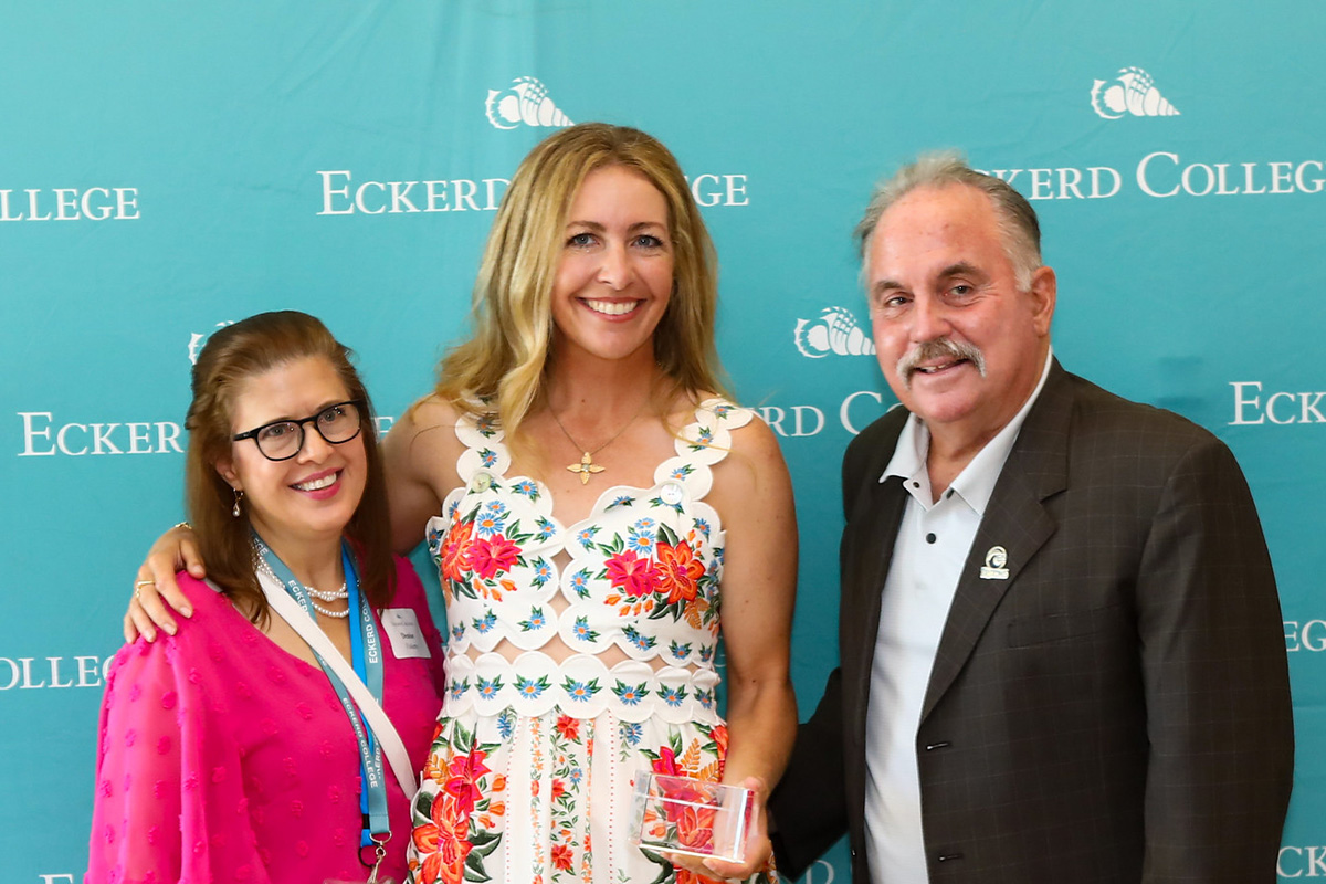 Woman in dress stands between professor and coach