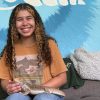 Student sits on a couch with a bearded dragon in her lap