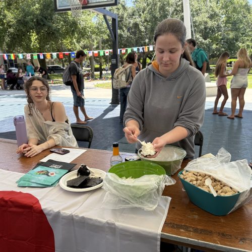 Two girls at a table draped with the flag of Japan. There are two bowls of food on the table.