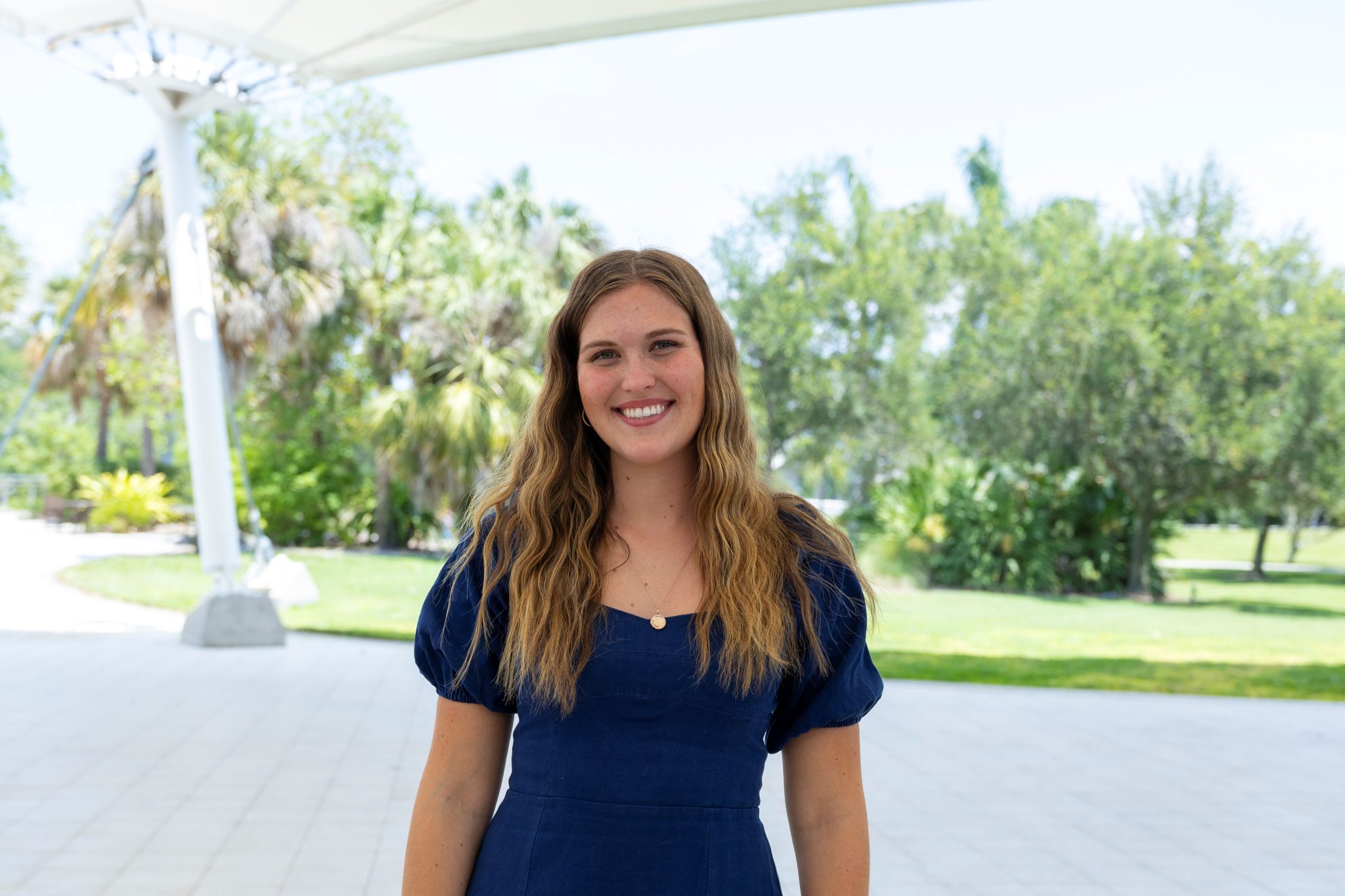 A female student standing outdoors in the shade.