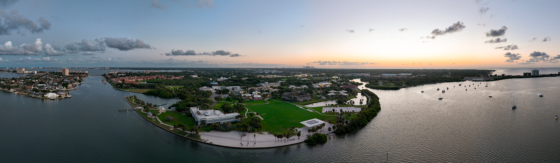 Aerial view of a college campus on a peninsula surrounded by water as the sun rises