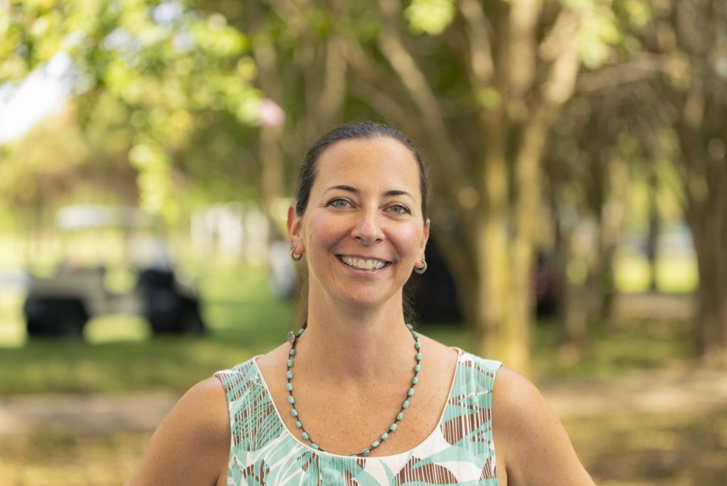 A woman standing in a wooded area.
