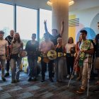 A group of college students stands together in a group in a well lit room.
