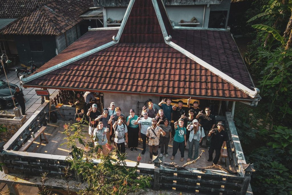 A group of young adults on a balcony waving upwards.