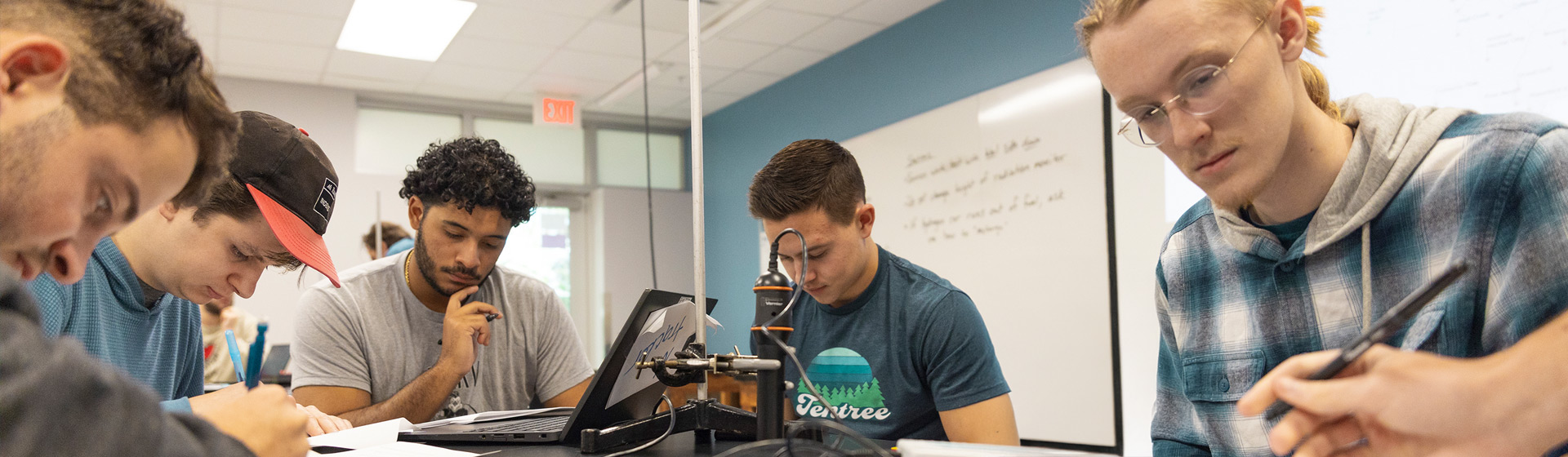 Students in physics lab work with equipment at a lab table