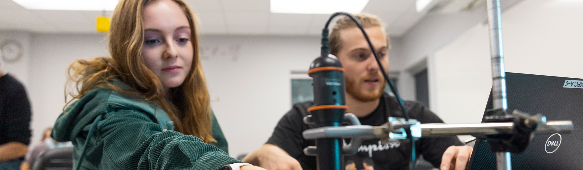Students in physics lab work with equipment at a lab table