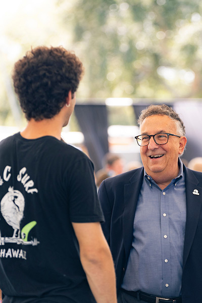 President Annarelli laughs while in discussion with an Eckerd College student in an outdoor setting