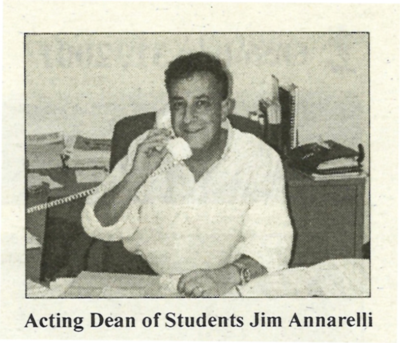 Black and white photo of a man in a white collared shirt with the sleeves rolled up smiles at the camera while picking up a white cord phone