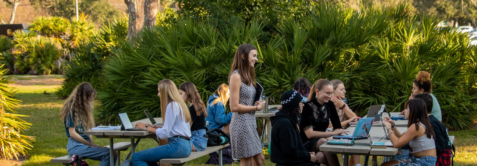 Professor teaching class outdoors at picnic tables