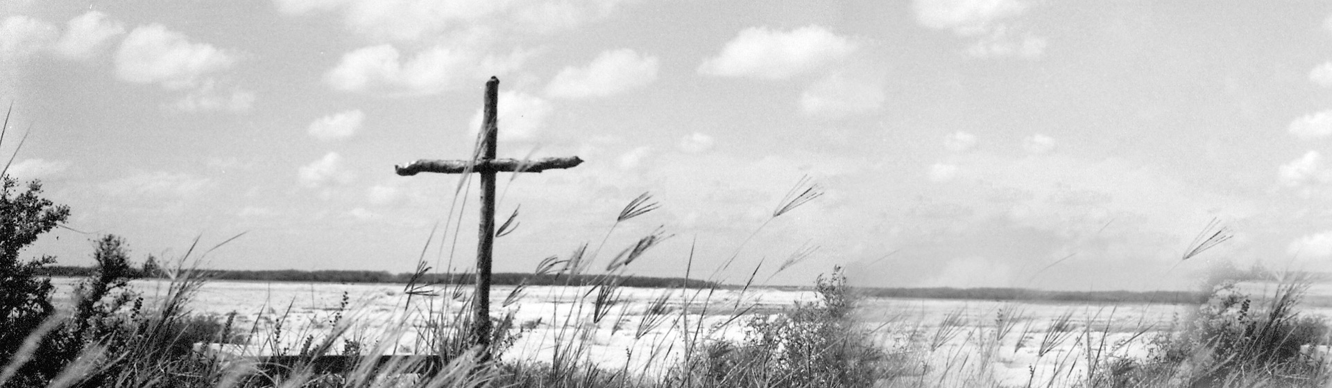 Wooden cross stuck in the ground on a sandy shoreline