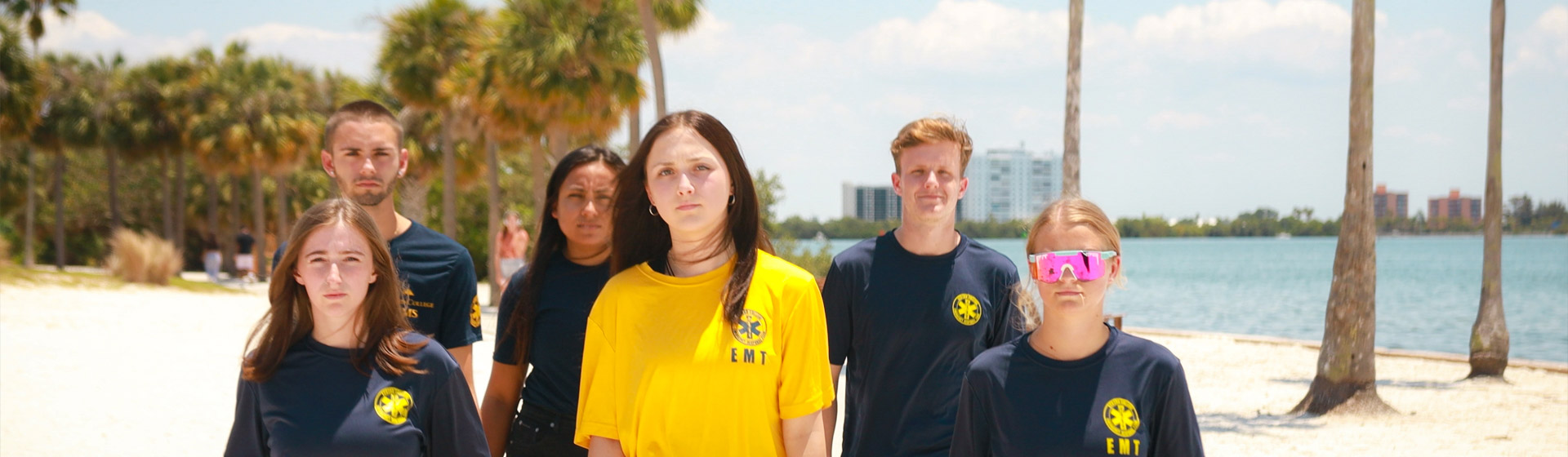 Group of Eckerd College students in uniforms on the beach