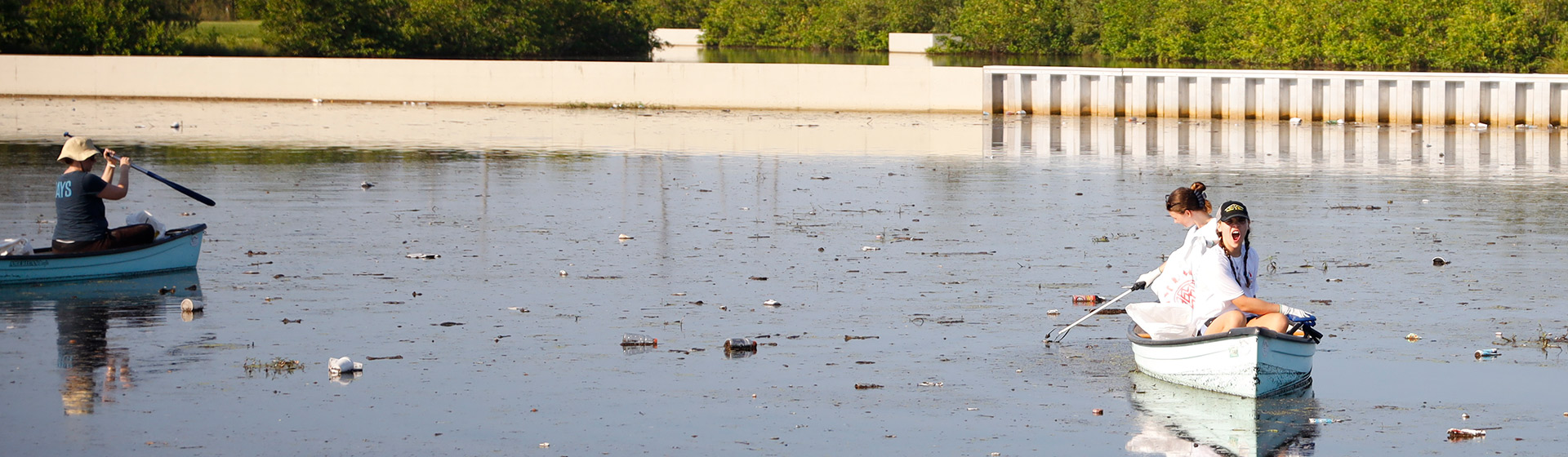 Student in canoe cleaning up trash in waterway