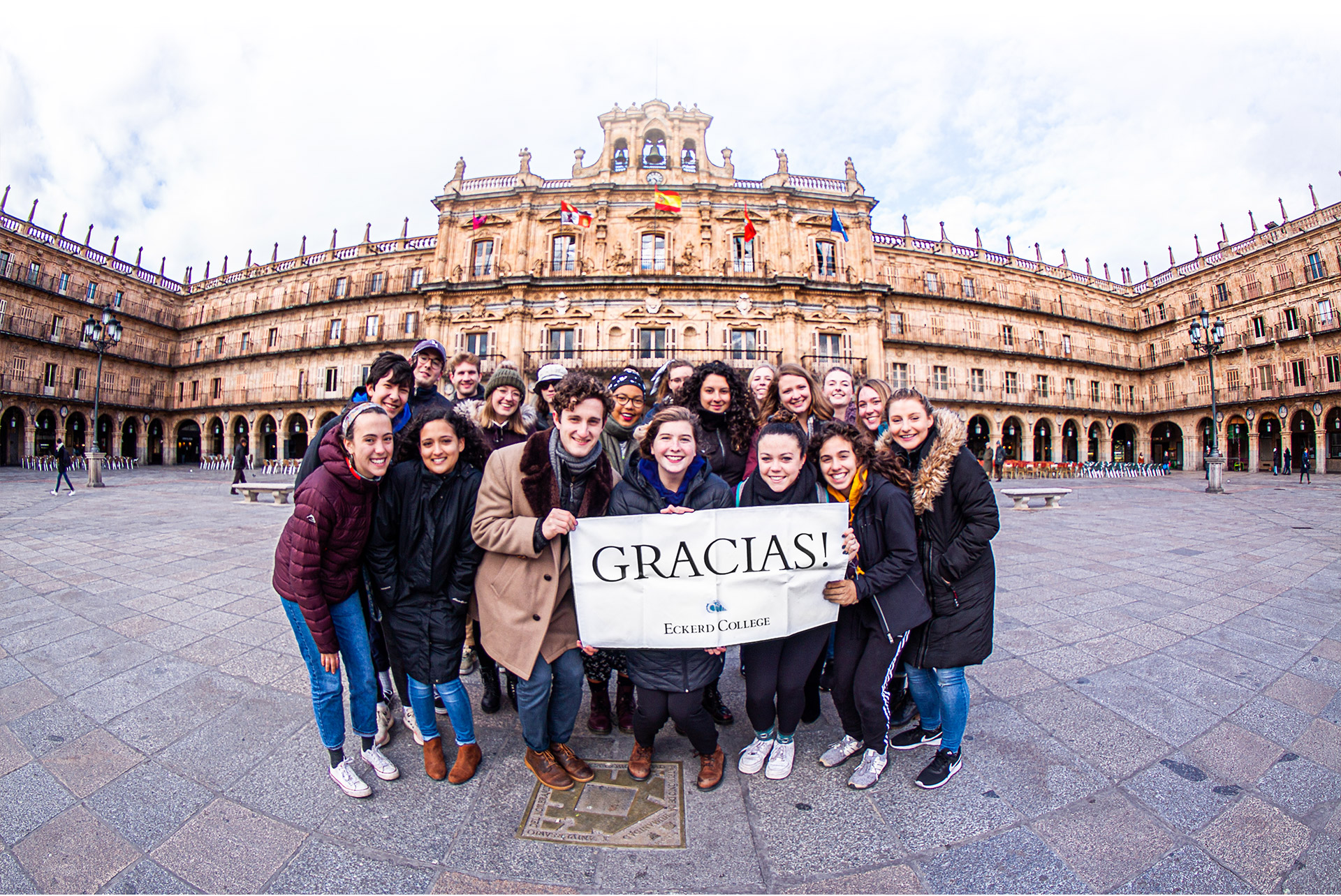 Eckerd College students gather in a plaza in Spain to hold a sign that says "Gracias"