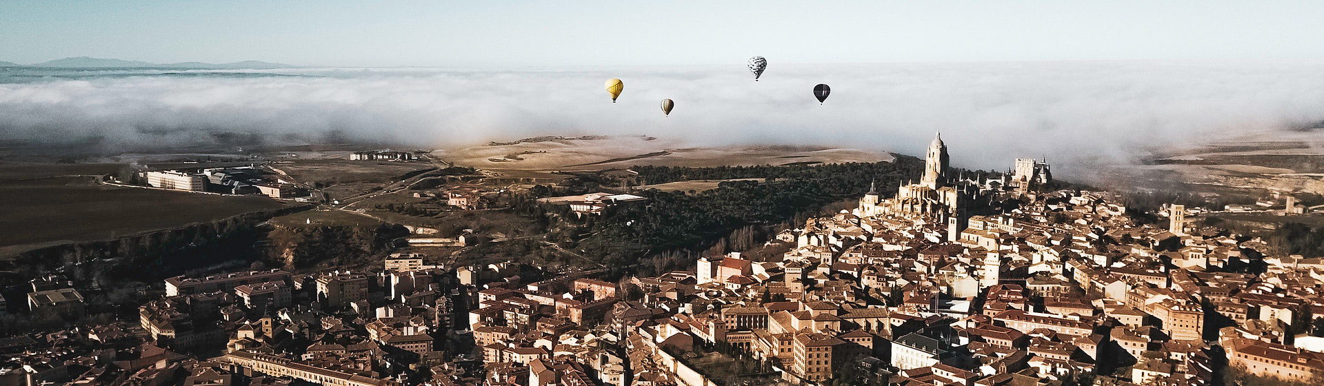 An aerial view of the city of Salamanca with hot air balloons rising about it