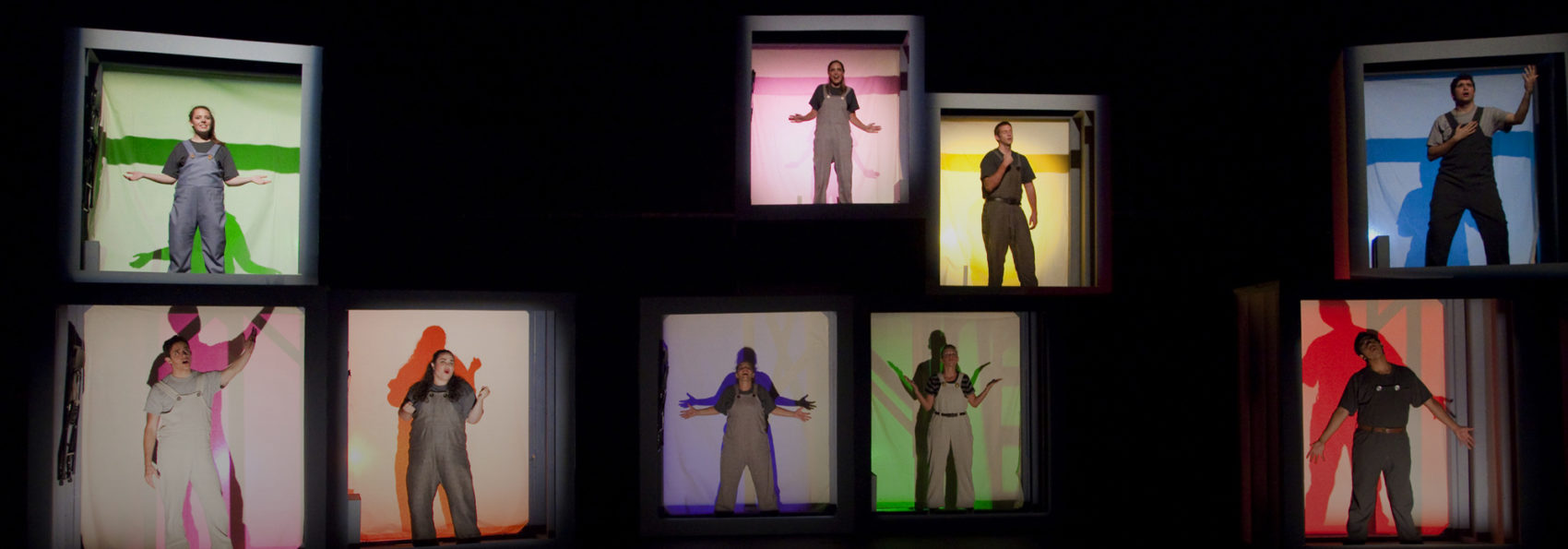 Student actors standing in different colored boxes on stage in a production of Working: A Musical