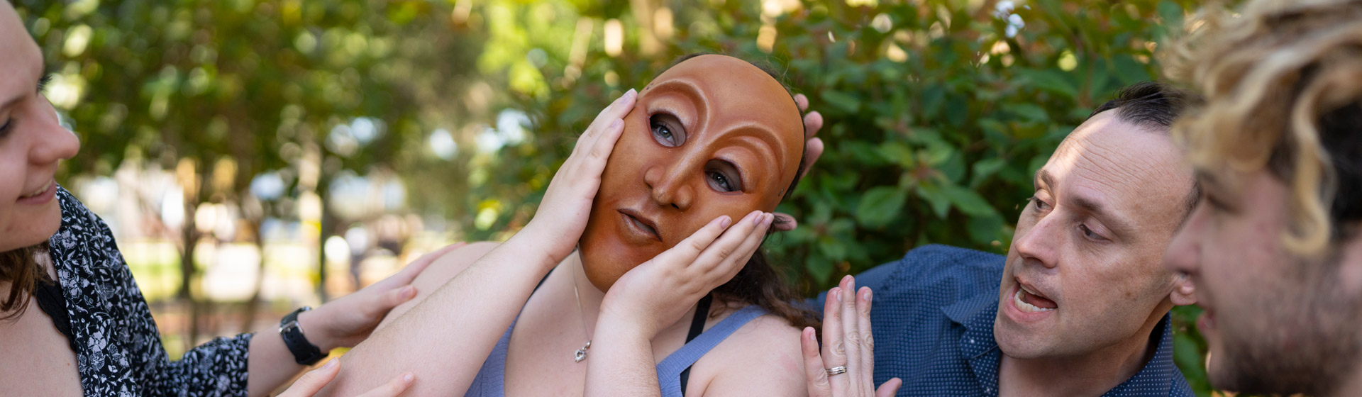 Student wearing mask puts hands to face while theatre professor and student encourage her