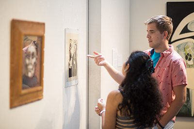 Two students discuss a piece of artwork in gallery