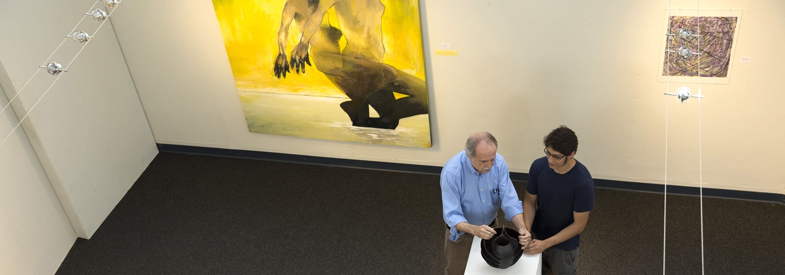 Professor Skinner discussing pottery with Visual Arts student Adrian Zuniga