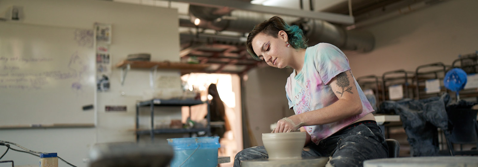 Visual Arts student throwing pottery on a wheel