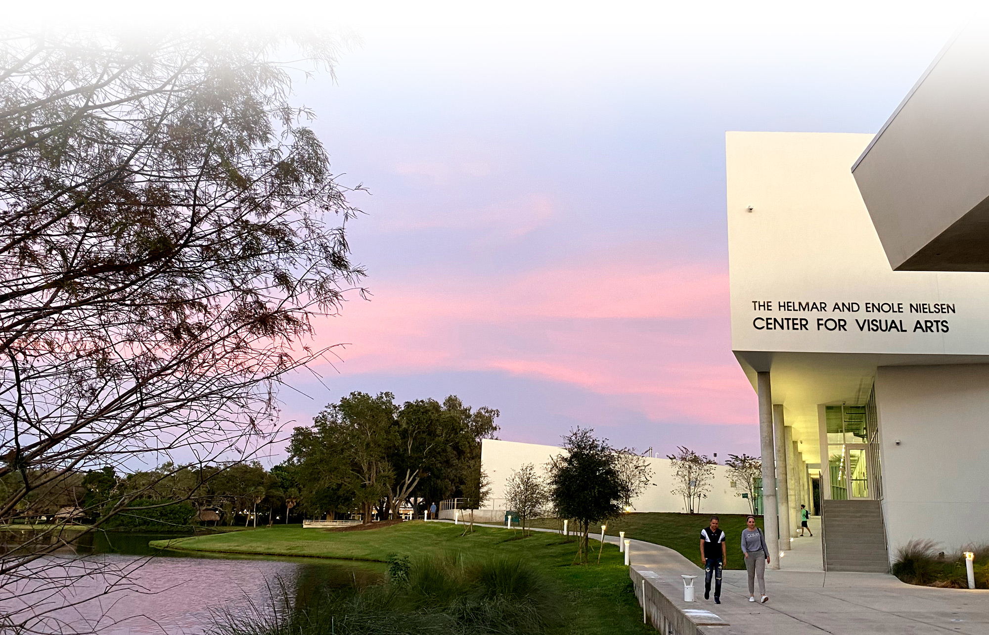 Visual arts students walk along the arts building under a Florida sunset