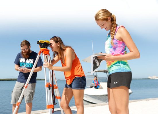 Two female students and one male student survey on South Beach with Geoscience and Marine Science Professor Laura Wetzel.