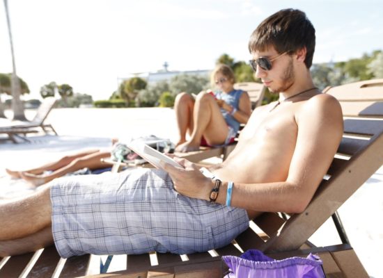 Male student reading in a lounge chair at South Beach