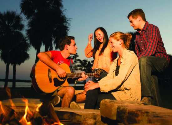 Students laughing and playing guitar at the South Beach fire pit