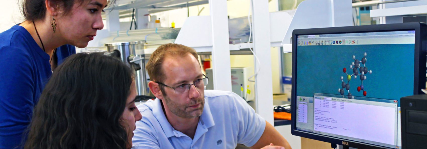 Assistant Professor of Chemistry Joe Larkin with two students looking at molecular structure on computer