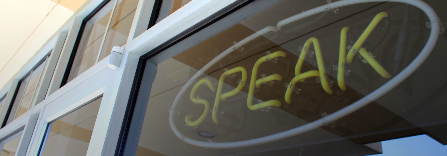 Neon sign that says "Speak" outside of Rahall Communication Center