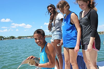First-year students on a boat, handling a ray