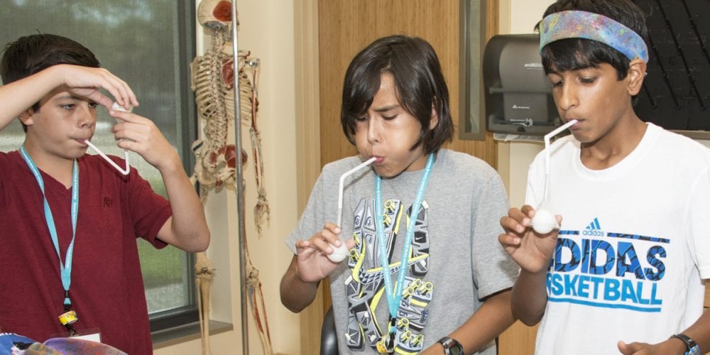 Students conducting science experiment with straws and balloons