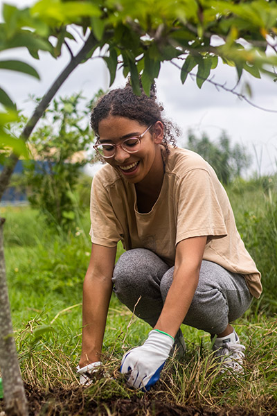 Eckerd student pulls weeds from the community farm