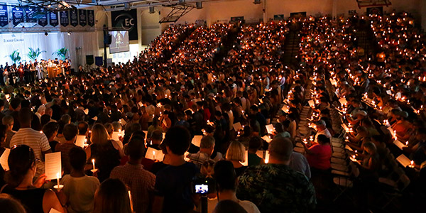 Families holding lit candles while reading