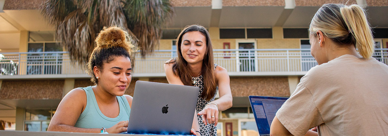 Student looking at laptop as professor points to screen