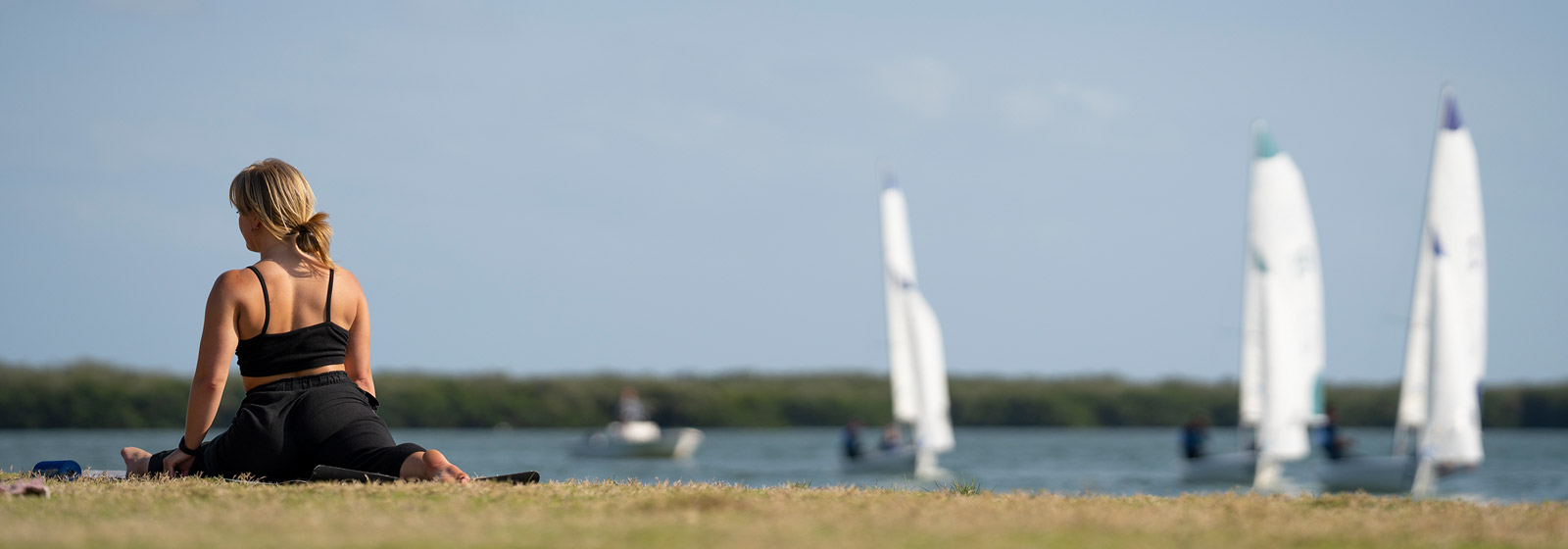 Student doing yoga outside while sailboats coast by