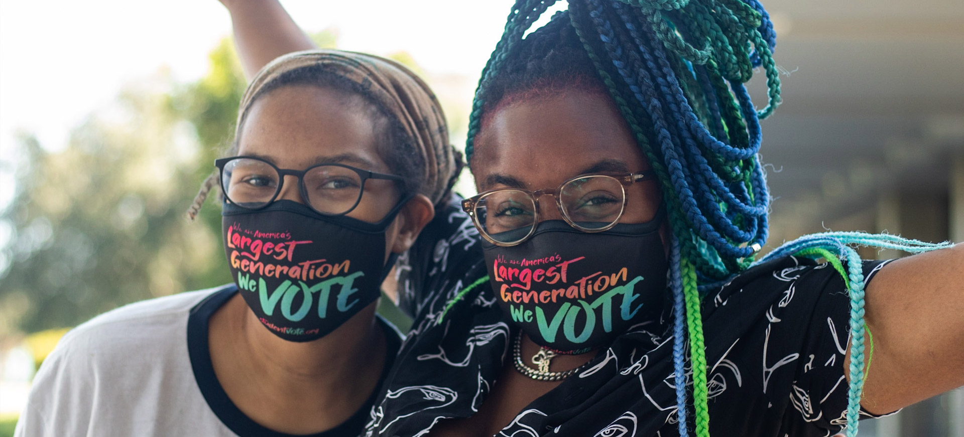 Two students wearing masks that say "VOTE"