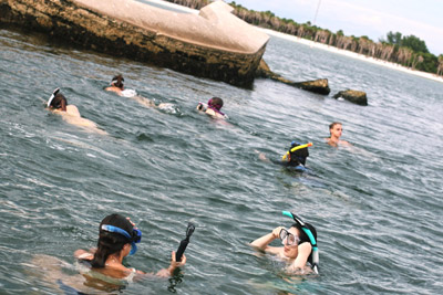 Students snorkeling in the water near large rocks