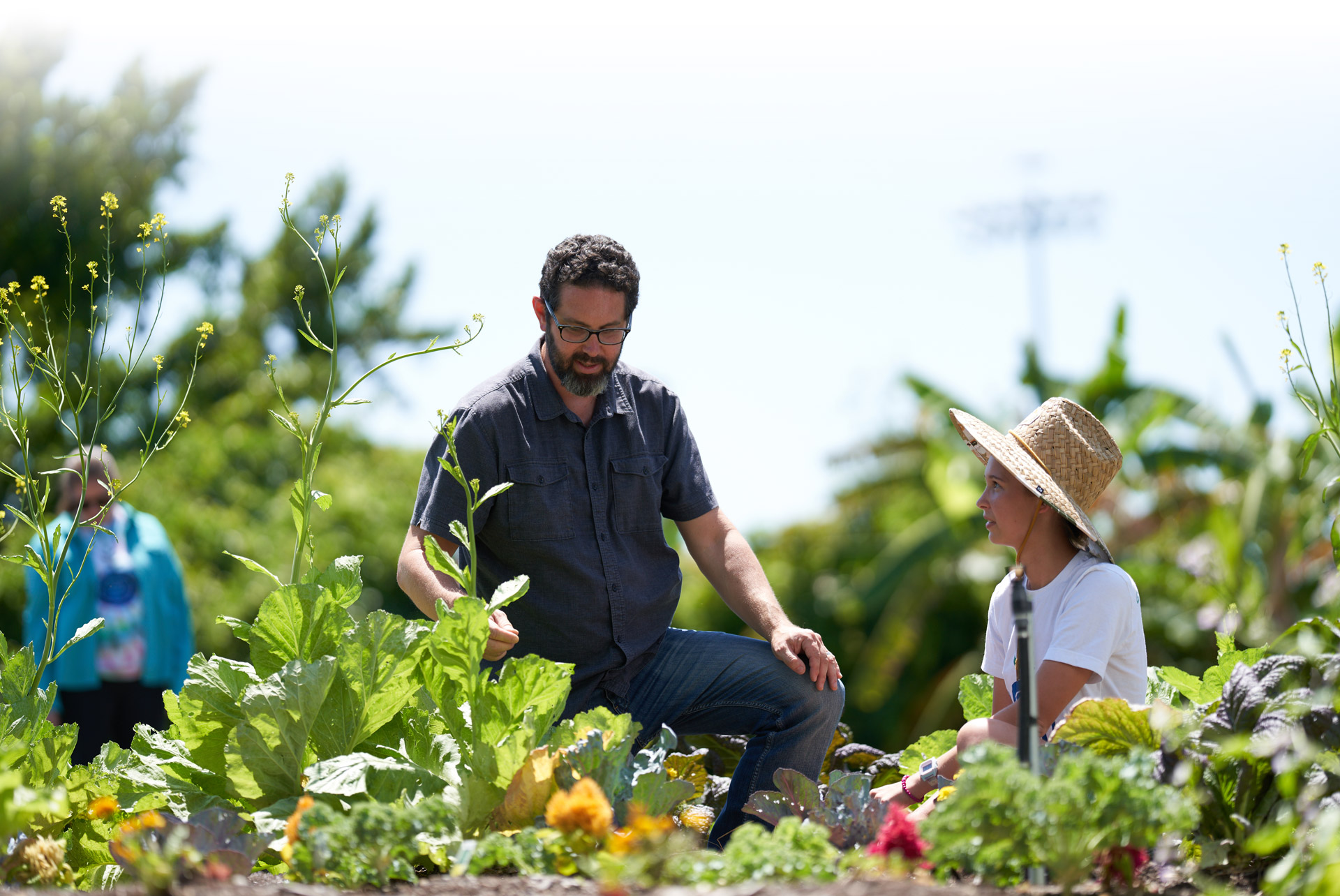 Professor and student in farmer's hat working in a farm bed