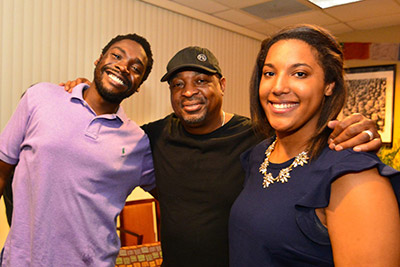 Rapper in hat poses with two Eckerd College students
