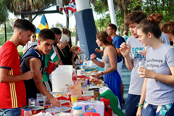 Students stand around a table decorated in a Spanish flag and covered with Spanish food