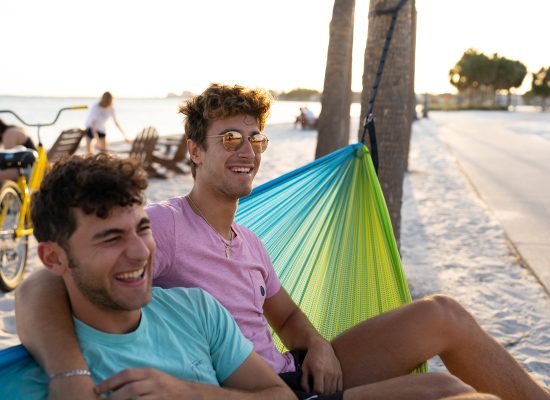 Eckerd College students swing in a hammock on the beach
