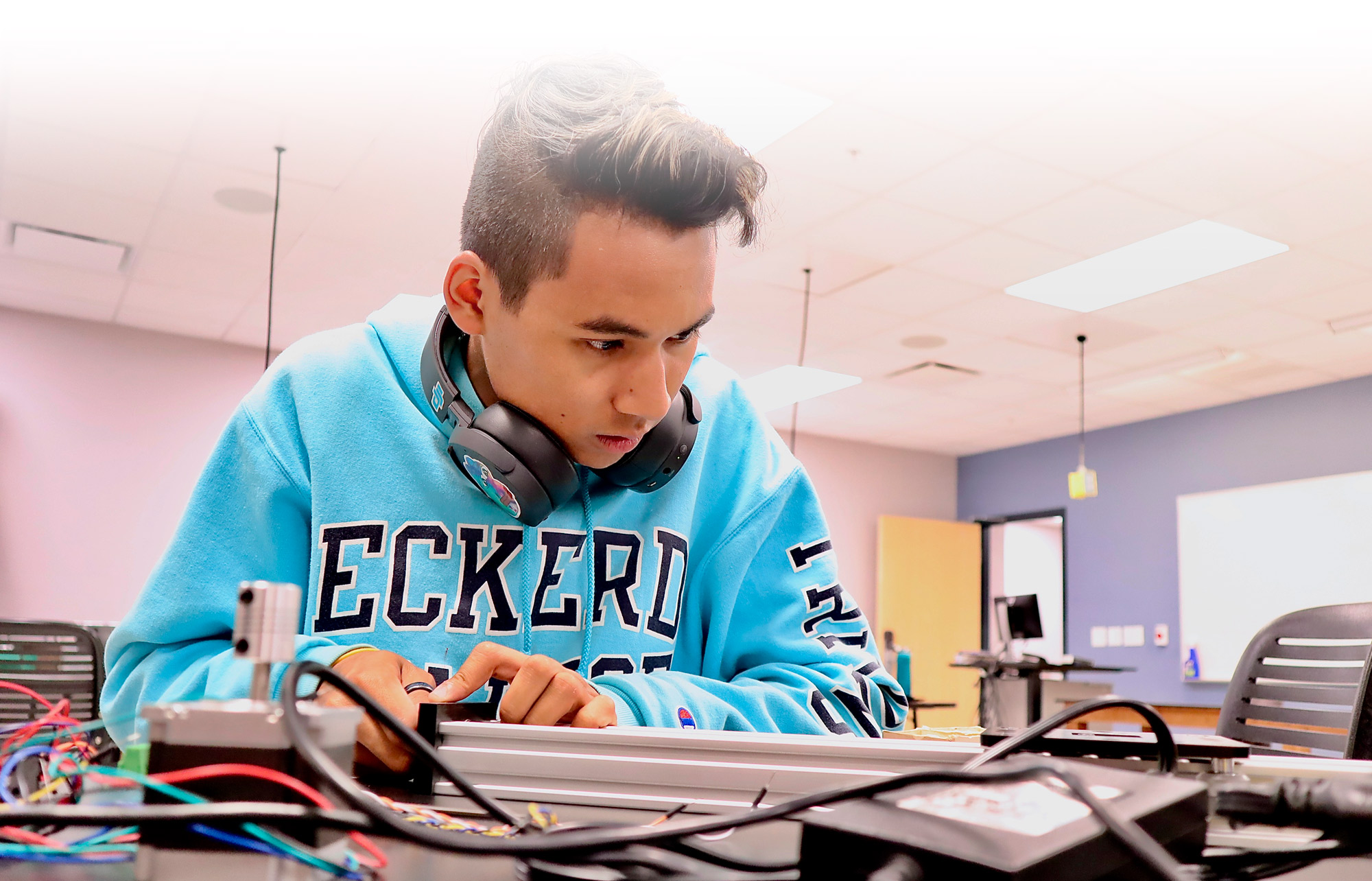 Student wearing a sweatshirt that reads "Eckerd" works with electrical circuits in a lab