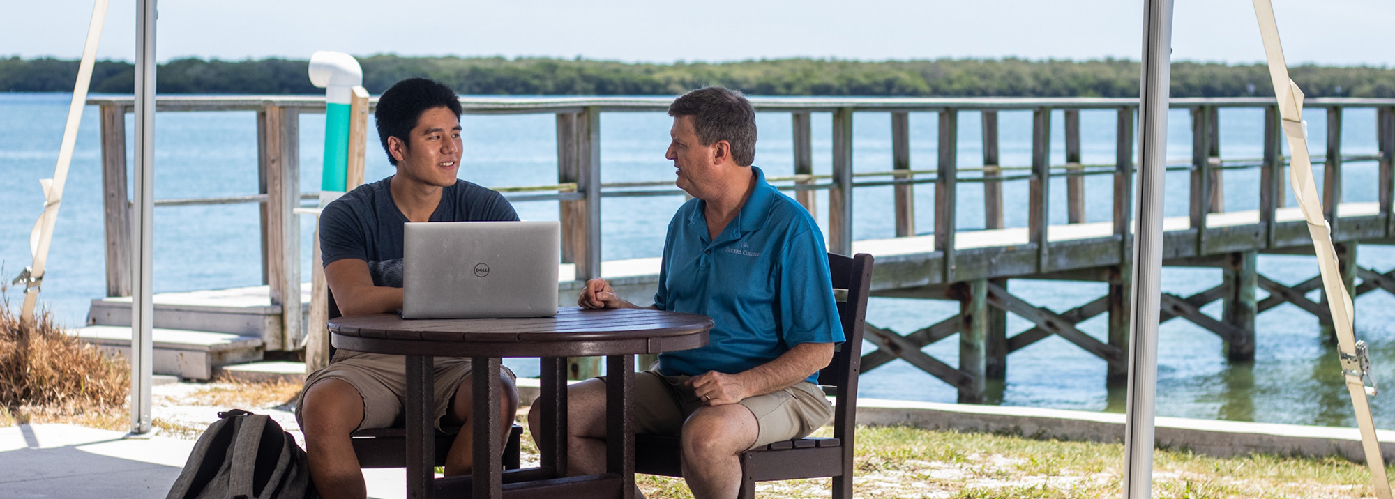 Computer Science professor and student on dock looking at laptop