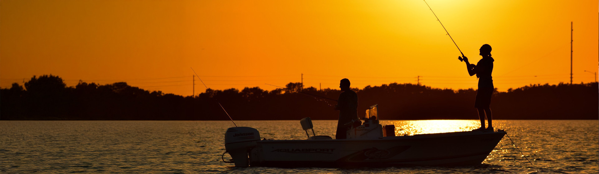 College students fishing from a boat at sunset