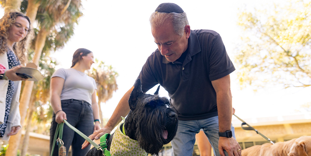 Rabbi pets a dog wearing a bandana