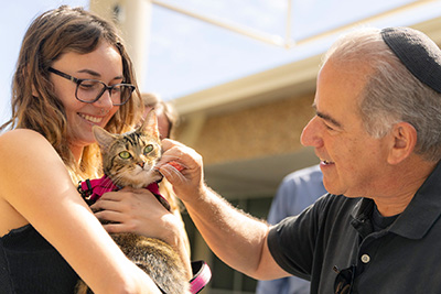 Rabbi pets a cat's cheek that a student is holding