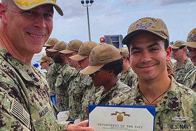 Young man in military fatigues receives certificate from older man